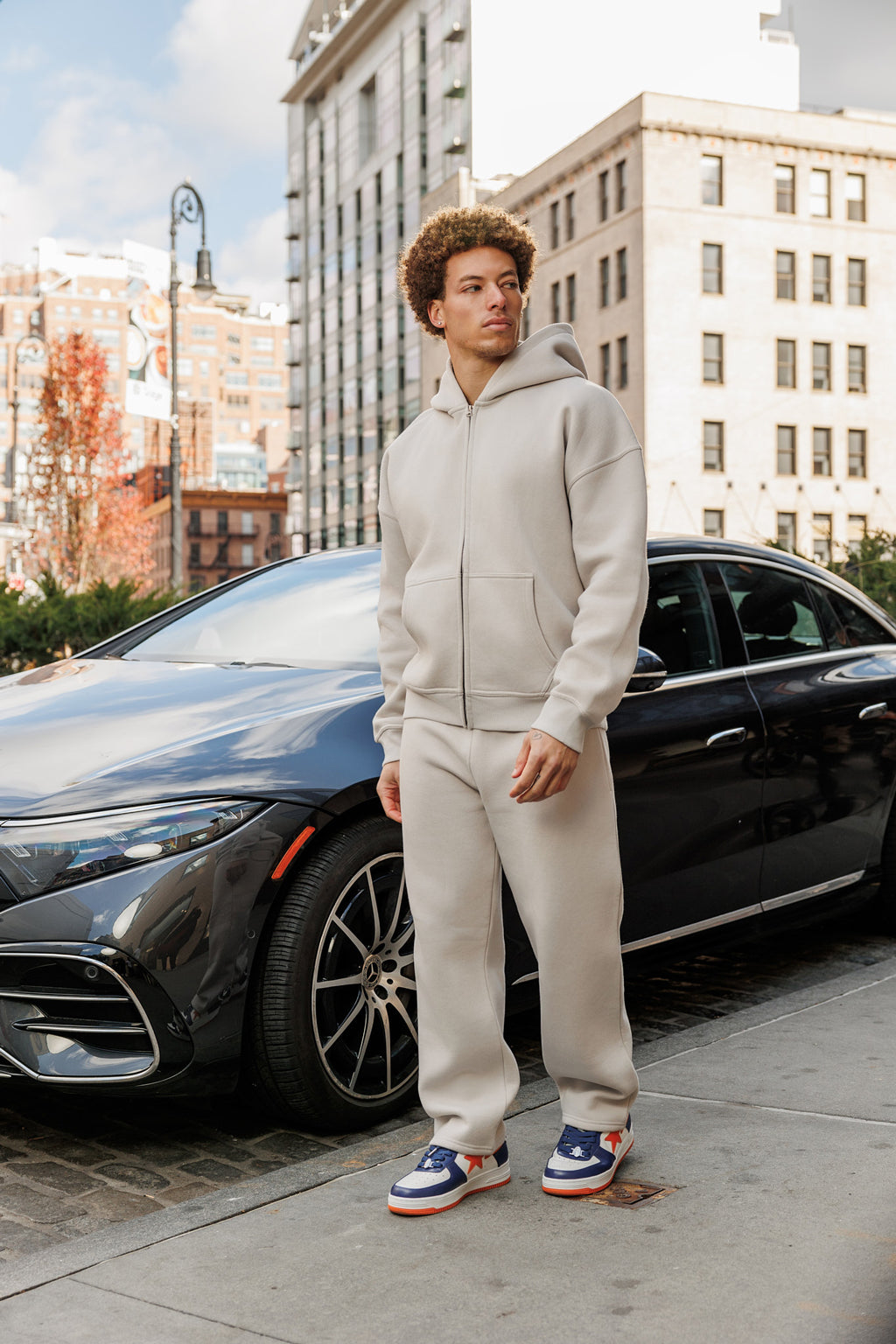 Model in a grey cotton polyester zip up hoodie and open hem sweatpants. Light Grey. In Manhattan, New York. Meatpacking District.